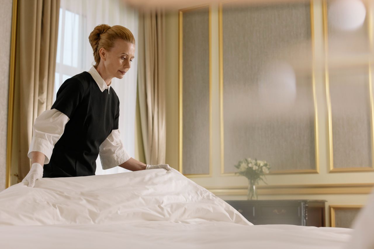 services-02 A professional housekeeper fixes a bed in a luxurious hotel room.
